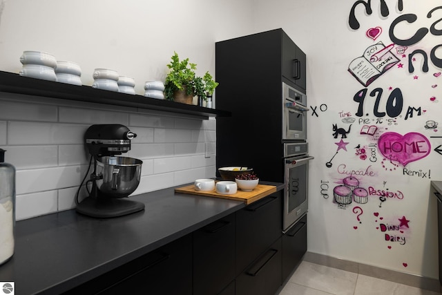 9371 Onominese Trl, Northport, MI 49670 - kitchen with dark cabinetry, open shelves, stainless steel oven, light tile patterned flooring, and decorative backsplash