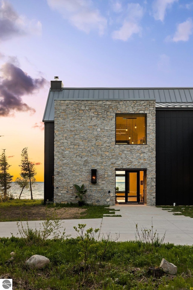 9371 Onominese Trl, Northport, MI 49670 - view of front facade featuring a standing seam roof, stone siding, metal roof, a chimney, and board and batten siding