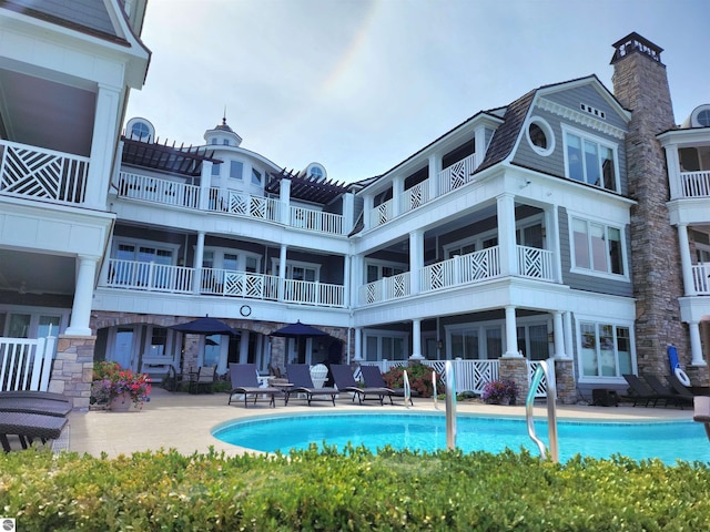 5707 S Lake St Unit 13F, Glen Arbor, MI 49636 - back of property featuring an outdoor pool, stone siding, a chimney, and a patio
