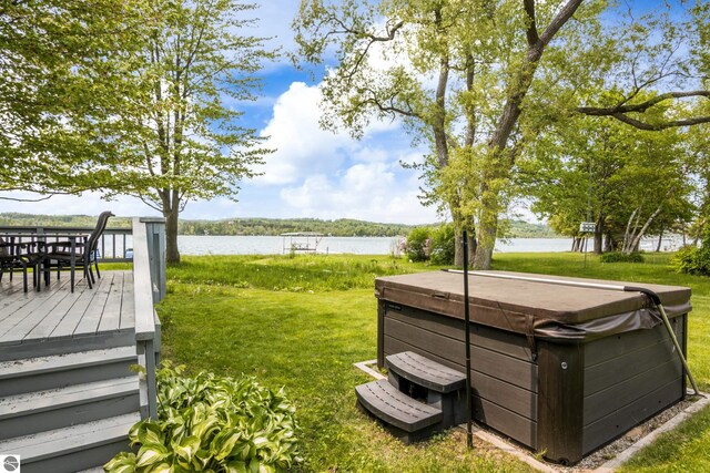 3802 S Grants Lndg, Lake Leelanau, MI 49653 - view of green lawn with a hot tub, outdoor dining area, and a deck with water view