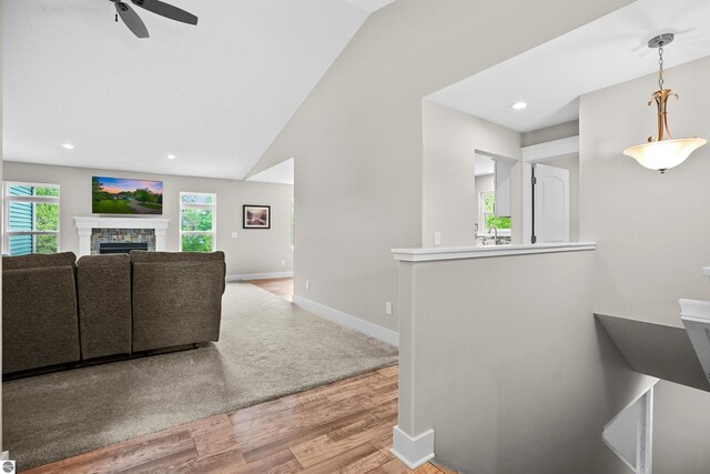 9207 Mockingbird Ln, Cadillac, MI 49601 - living area featuring wood finished floors, ceiling fan, a fireplace, baseboards, and vaulted ceiling