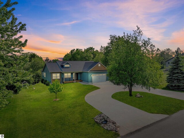9207 Mockingbird Ln, Cadillac, MI 49601 - view of front of home featuring concrete driveway, a lawn, and a garage