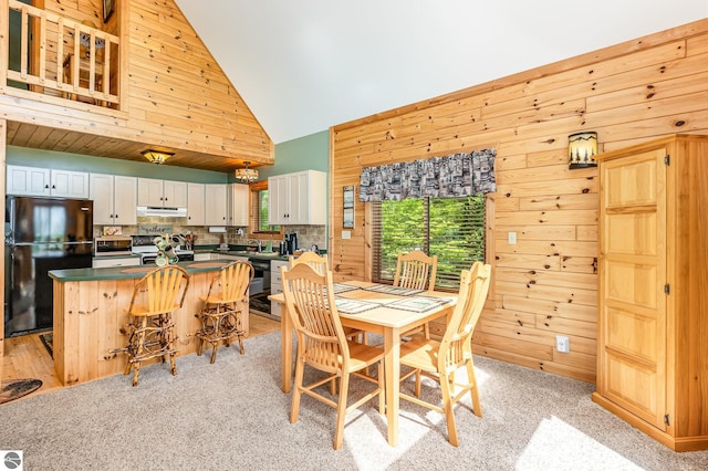 1715 Sunrise Dr, Greenbush, MI 48738 - dining room featuring wooden walls, high vaulted ceiling, and light colored carpet