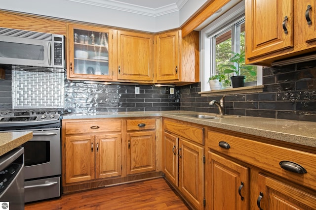 2664 Chandler Rd, Traverse City, MI 49686 - kitchen featuring appliances with stainless steel finishes, ornamental molding, a sink, brown cabinetry, and dark wood-type flooring
