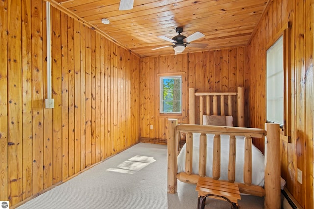 2664 Chandler Rd, Traverse City, MI 49686 - unfurnished bedroom with wood ceiling, baseboard heating, carpet floors, wood walls, and a ceiling fan