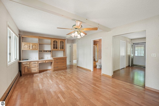 9017 Clam Lake Rd, Bellaire, MI 49615 - unfurnished living room with baseboard heating, light wood-style floors, a textured ceiling, a ceiling fan, and beam ceiling