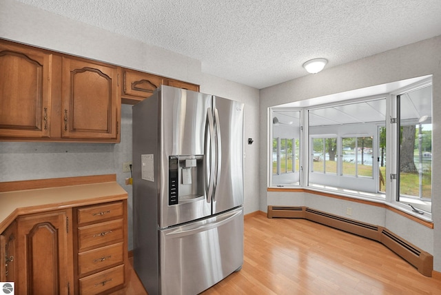 9017 Clam Lake Rd, Bellaire, MI 49615 - kitchen with stainless steel fridge with ice dispenser, a baseboard heating unit, brown cabinetry, a textured ceiling, and light wood finished floors