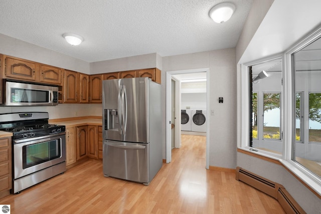 9017 Clam Lake Rd, Bellaire, MI 49615 - kitchen featuring appliances with stainless steel finishes, independent washer and dryer, a baseboard radiator, light wood-style floors, and brown cabinetry