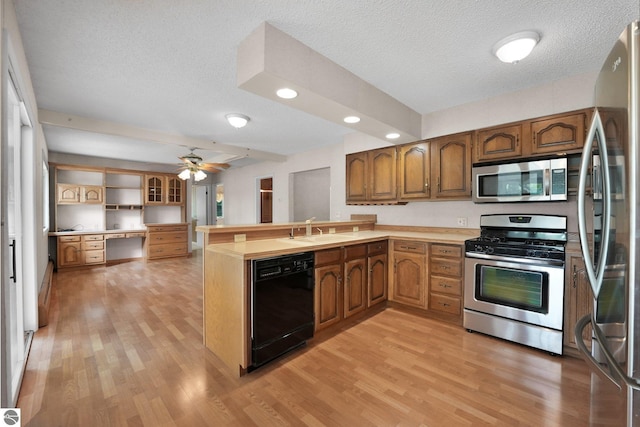 9017 Clam Lake Rd, Bellaire, MI 49615 - kitchen with appliances with stainless steel finishes, a sink, a peninsula, light wood-type flooring, and brown cabinetry