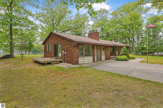 9017 Clam Lake Rd, Bellaire, MI 49615 - view of front of property with asphalt driveway, a front lawn, a chimney, and brick siding