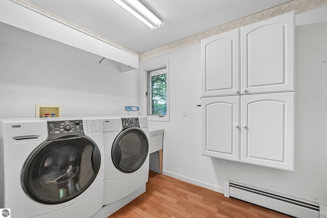 9017 Clam Lake Rd, Bellaire, MI 49615 - washroom featuring baseboard heating, cabinet space, washer and clothes dryer, light wood-style flooring, and baseboards