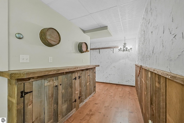 9017 Clam Lake Rd, Bellaire, MI 49615 - bar area with light wood-type flooring, a chandelier, and baseboards
