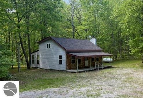 350 Mcmorris Trl, Harrison, MI 48625 - view of front of property featuring a porch, a wooded view, and a chimney