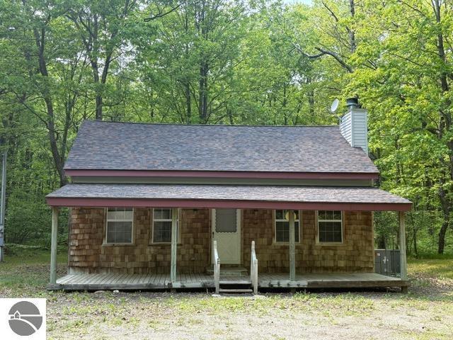 350 Mcmorris Trl, Harrison, MI 48625 - view of front of house featuring a chimney, a porch, and a shingled roof