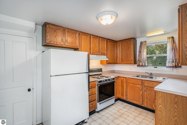 212 Palmer St, Mount Pleasant, MI 48858 - kitchen with white appliances, under cabinet range hood, a sink, light countertops, and brown cabinets