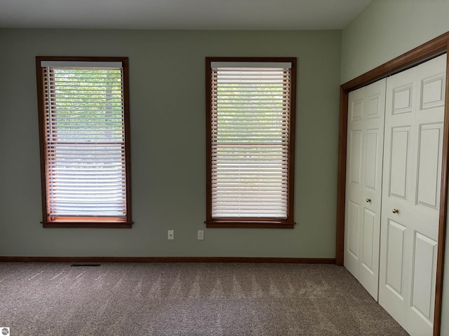5867 Huron Woods Dr, Tawas City, MI 48763 - unfurnished bedroom with carpet, a closet, baseboards, and multiple windows