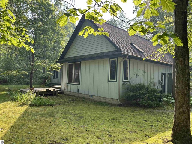 5867 Huron Woods Dr, Tawas City, MI 48763 - view of side of property featuring a yard, a shingled roof, and board and batten siding