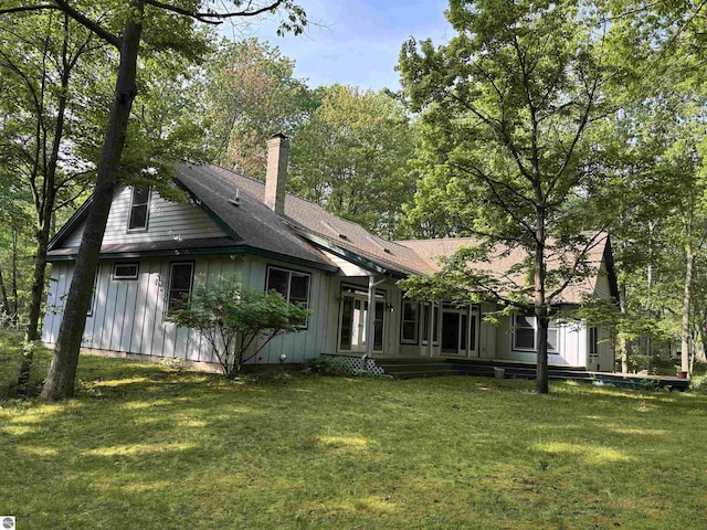 5867 Huron Woods Dr, Tawas City, MI 48763 - rear view of property with a chimney, a yard, and board and batten siding
