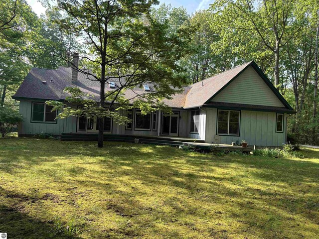 5867 Huron Woods Dr, Tawas City, MI 48763 - back of property with a yard, a chimney, and a shingled roof