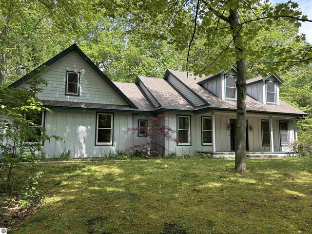 5867 Huron Woods Dr, Tawas City, MI 48763 - view of front of home featuring board and batten siding, a front yard, covered porch, and a shingled roof