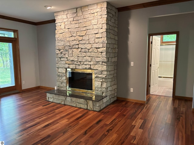 5867 Huron Woods Dr, Tawas City, MI 48763 - unfurnished living room featuring crown molding, a stone fireplace, wood finished floors, and baseboards