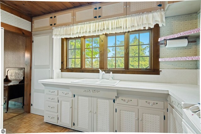 12570 N Cathead Point Rd, Northport, MI 49670 - kitchen featuring wallpapered walls, a sink, light countertops, and white cabinets