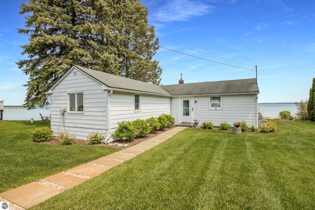 5896 S Cummings St, Suttons Bay, MI 49682 - view of front of house featuring a front lawn, a shingled roof, and a chimney
