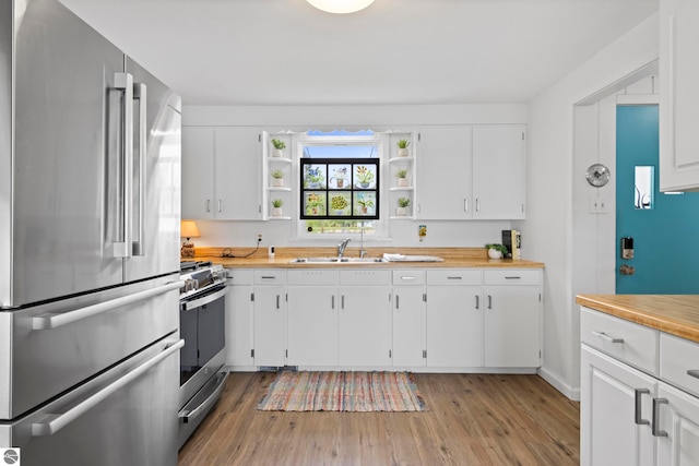 5896 S Cummings St, Suttons Bay, MI 49682 - kitchen with stainless steel appliances, a sink, open shelves, light wood-style flooring, and white cabinetry
