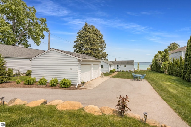 5896 S Cummings St, Suttons Bay, MI 49682 - back of house featuring a detached garage, an outbuilding, a lawn, and a water view