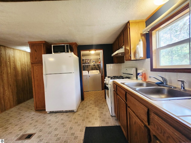3764 E N Down River Rd, Grayling, MI 49738 - kitchen featuring white appliances, under cabinet range hood, washing machine and clothes dryer, a sink, and tile counters