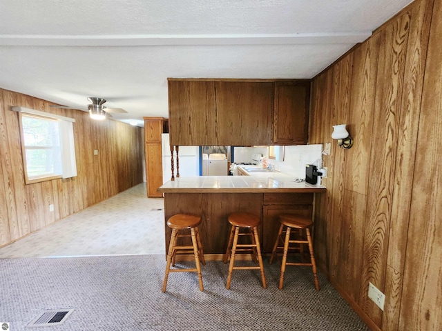 3764 E N Down River Rd, Grayling, MI 49738 - kitchen featuring wooden walls, washer / dryer, fridge, a breakfast bar area, and brown cabinetry