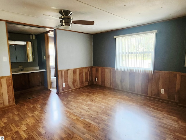 3764 E N Down River Rd, Grayling, MI 49738 - spare room with a wainscoted wall, wood finished floors, a ceiling fan, a sink, and wood walls