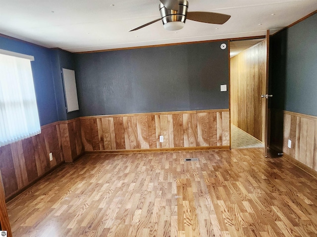 3764 E N Down River Rd, Grayling, MI 49738 - empty room featuring wood finished floors, a ceiling fan, wood walls, and a wainscoted wall