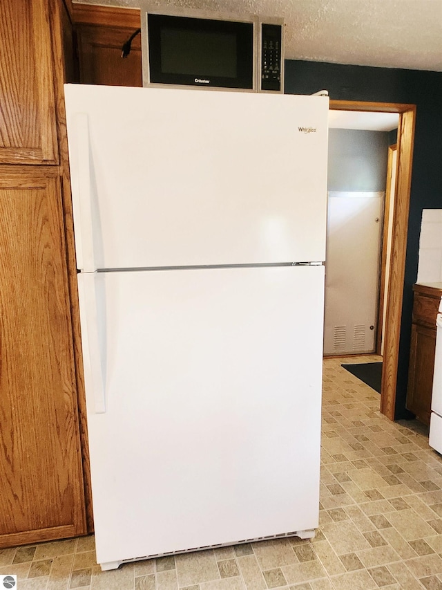3764 E N Down River Rd, Grayling, MI 49738 - kitchen with freestanding refrigerator and brown cabinets