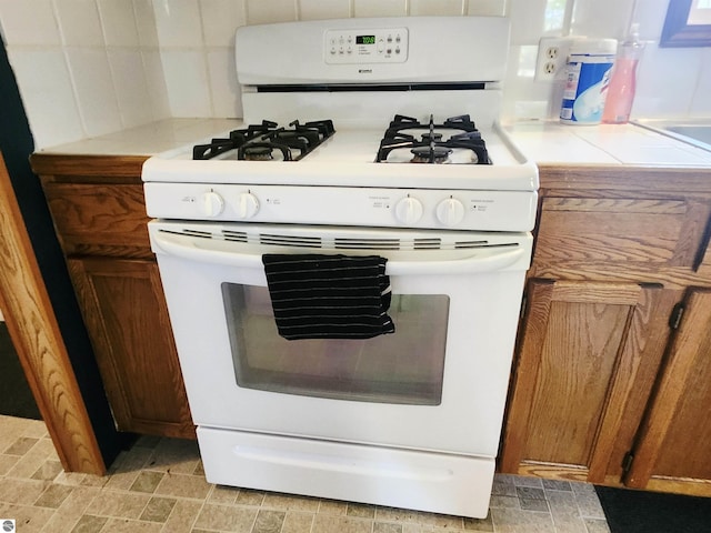 3764 E N Down River Rd, Grayling, MI 49738 - kitchen with white gas range oven, light countertops, and brown cabinetry