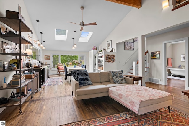 3362 S French Rd, Cedar, MI 49621 - living room featuring high vaulted ceiling, hardwood / wood-style flooring, a skylight, stairway, and baseboards