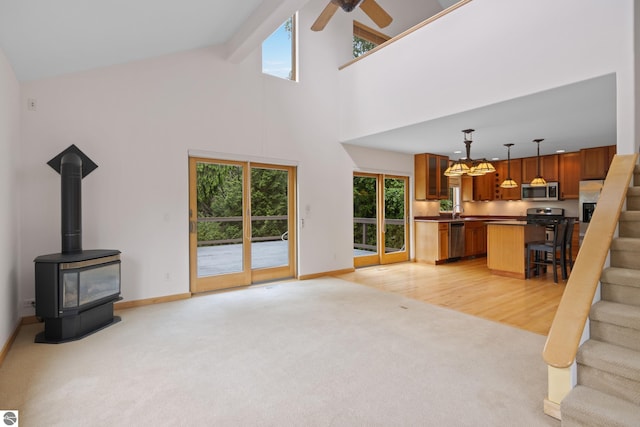 110 W Terrace Lane Commons, Leland, MI 49654 - unfurnished living room featuring light carpet, plenty of natural light, high vaulted ceiling, baseboards, and stairway