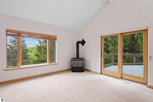 110 W Terrace Lane Commons, Leland, MI 49654 - unfurnished living room featuring baseboards, carpet floors, a wood stove, and high vaulted ceiling