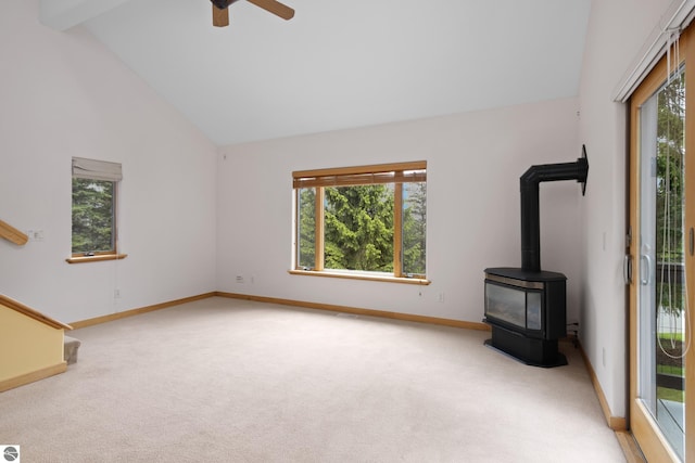 110 W Terrace Lane Commons, Leland, MI 49654 - unfurnished living room with light colored carpet, healthy amount of natural light, baseboards, high vaulted ceiling, and a wood stove