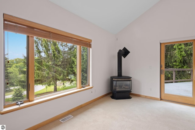 110 W Terrace Lane Commons, Leland, MI 49654 - unfurnished living room with light carpet, baseboards, lofted ceiling, and a wood stove