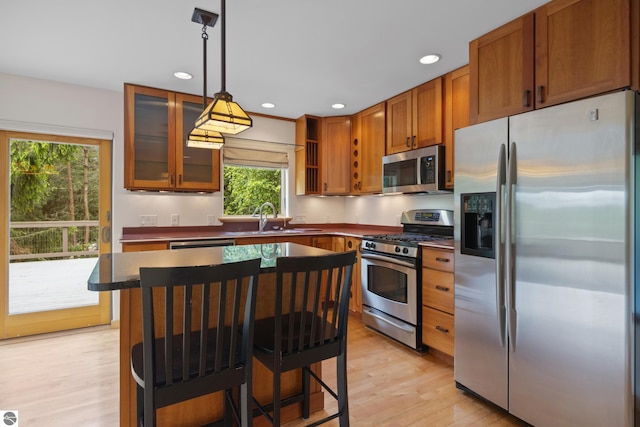 110 W Terrace Lane Commons, Leland, MI 49654 - kitchen with appliances with stainless steel finishes, dark countertops, light wood finished floors, glass insert cabinets, and decorative light fixtures