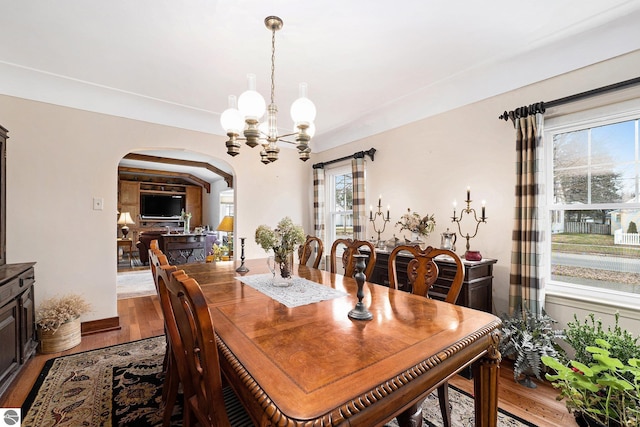 739 Stimson St, Cadillac, MI 49601 - dining room with arched walkways, a chandelier, light wood-type flooring, and baseboards