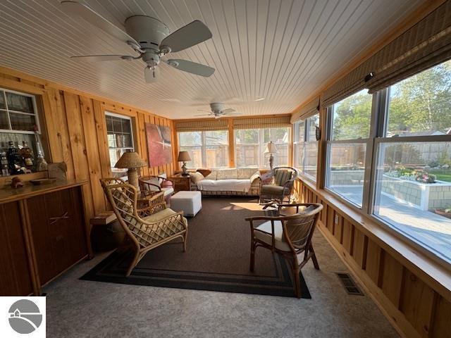 739 Stimson St, Cadillac, MI 49601 - sunroom featuring plenty of natural light, carpet flooring, wooden walls, a ceiling fan, and wooden ceiling