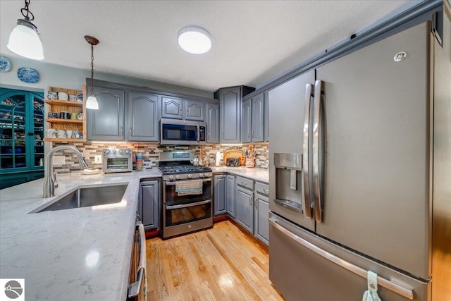 6369 Wooded Trl, Houghton Lake, MI 48629 - kitchen with appliances with stainless steel finishes, gray cabinets, decorative backsplash, light wood-style floors, and light stone countertops