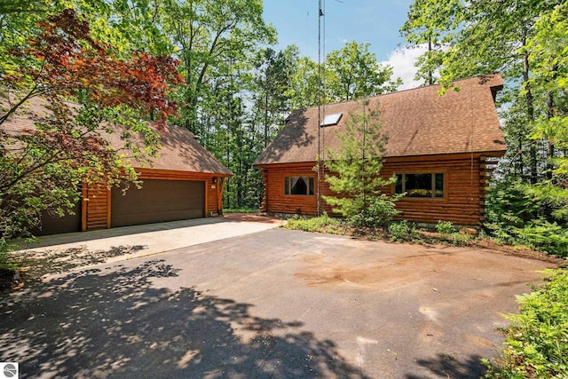 10037 Mud Lake Rd, Interlochen, MI 49643 - log-style house featuring a garage, asphalt driveway, log siding, an outdoor structure, and roof with shingles