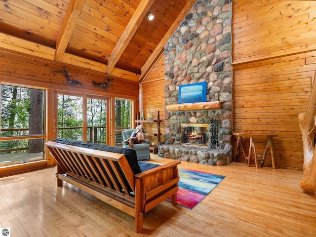 10037 Mud Lake Rd, Interlochen, MI 49643 - living room featuring healthy amount of natural light, hardwood / wood-style floors, a wooden ceiling with exposed beams, wooden walls, and a fireplace