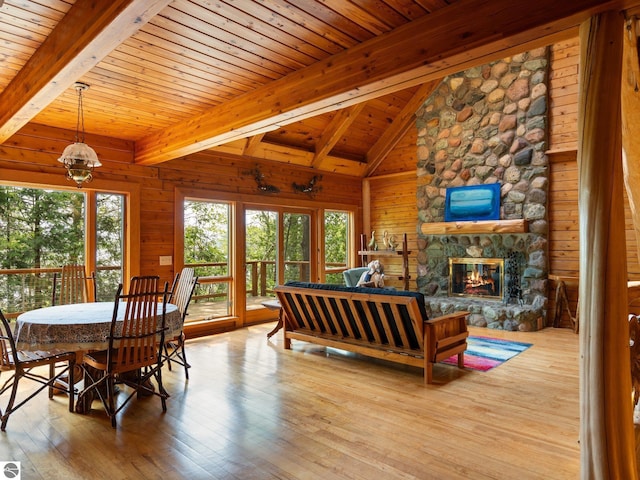 10037 Mud Lake Rd, Interlochen, MI 49643 - dining room with wood ceiling, hardwood / wood-style floors, wood walls, and a stone fireplace