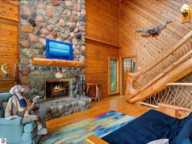 10037 Mud Lake Rd, Interlochen, MI 49643 - living area with wood finished floors, a stone fireplace, wood walls, and a towering ceiling