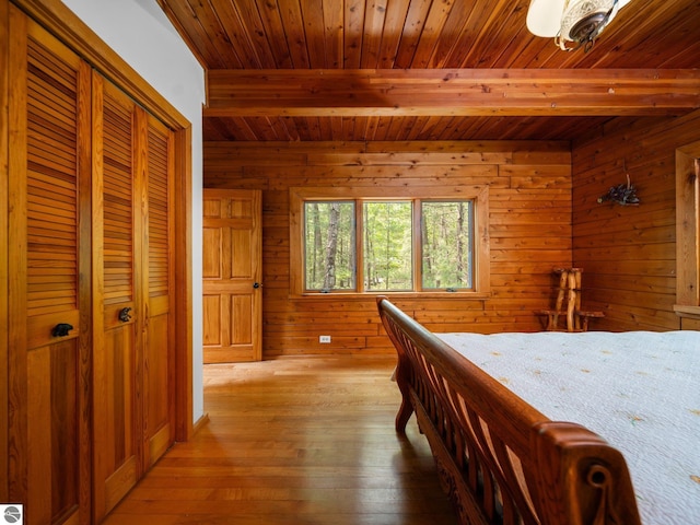10037 Mud Lake Rd, Interlochen, MI 49643 - bedroom with a wooden ceiling with exposed beams, light wood finished floors, wood walls, and a closet
