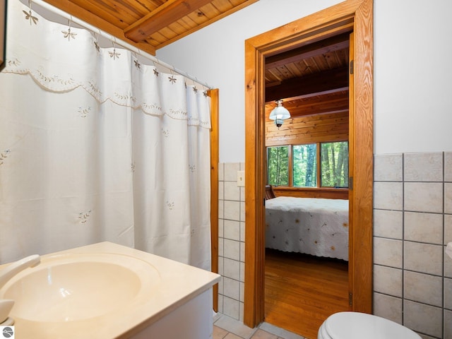 10037 Mud Lake Rd, Interlochen, MI 49643 - bathroom with a wooden ceiling with exposed beams, tile walls, vanity, and connected bathroom